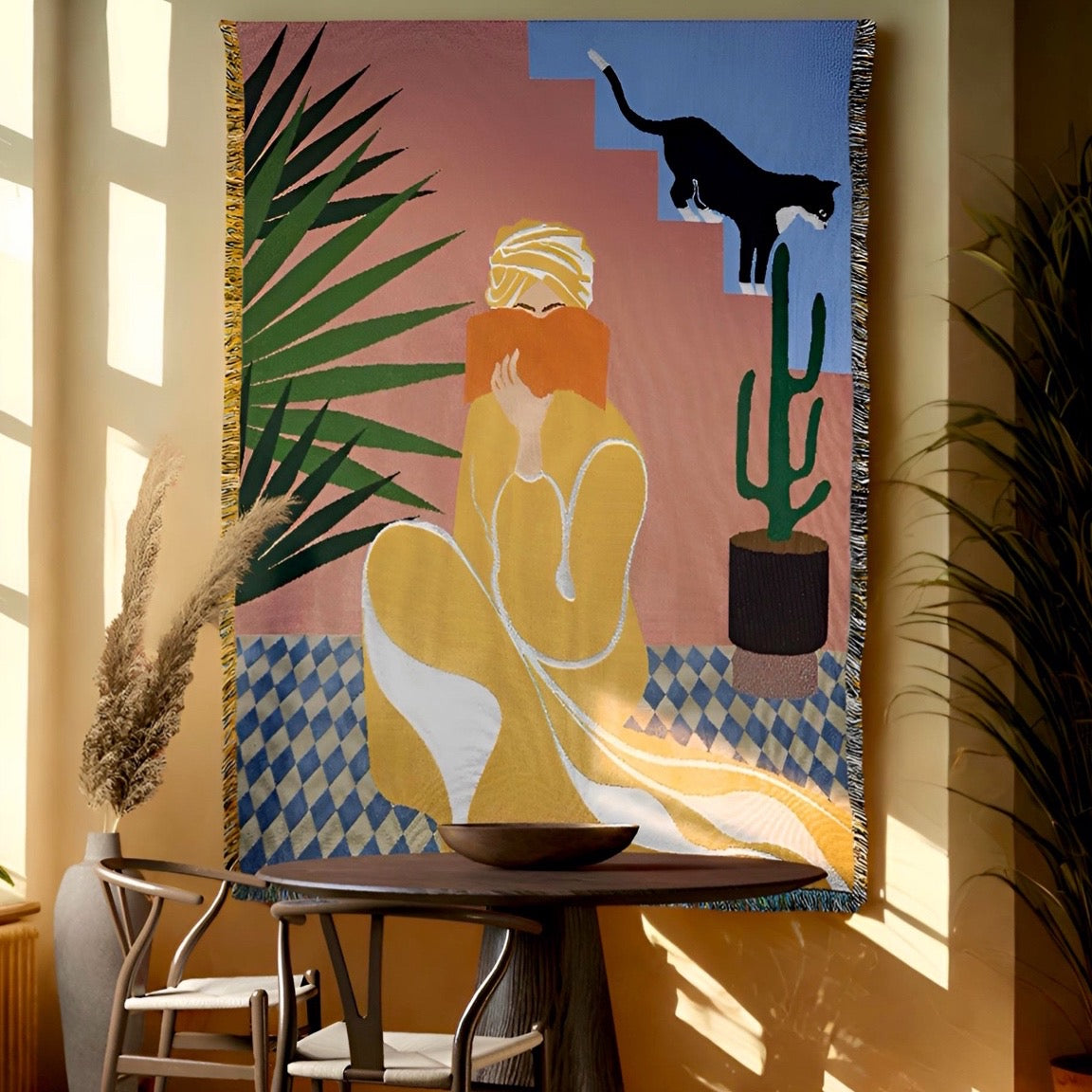 atelier yuchi  marrakech woven throw tapestry with a woman, panther, and cactus design in a room with plants and a table.